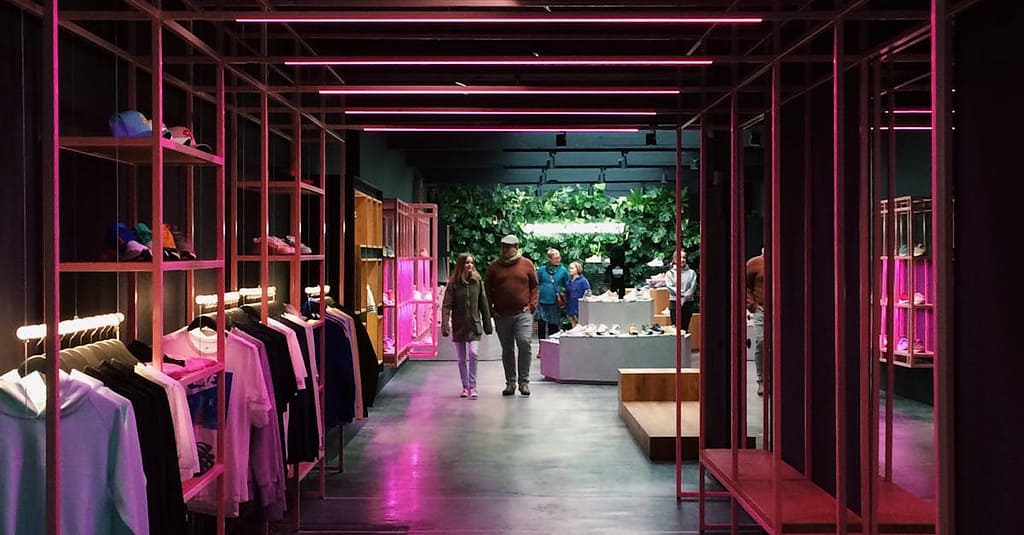 Interior of a modern clothing store in Antwerp, featuring neon pink lights and a sleek design.