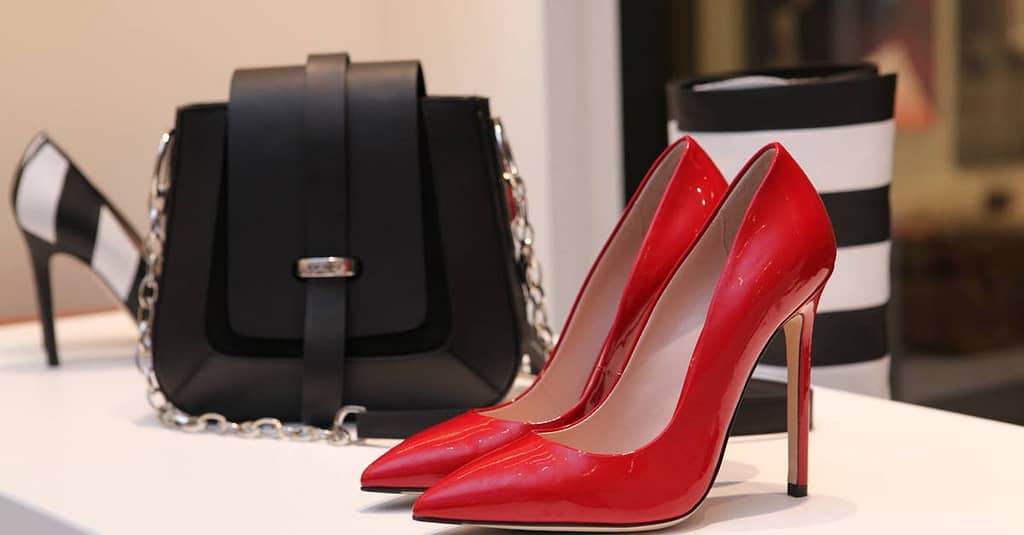 Showcasing sleek red stilettos and a chic black handbag in a luxury boutique setting.